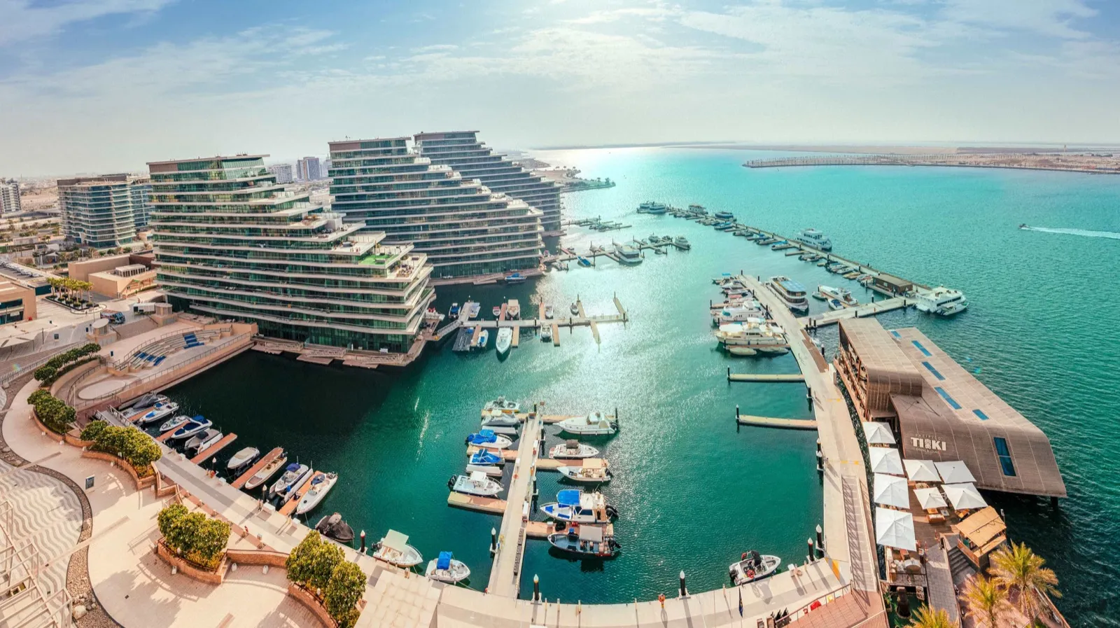 Aerial view of a marina and terraced waterfront residences at Al Raha Beach