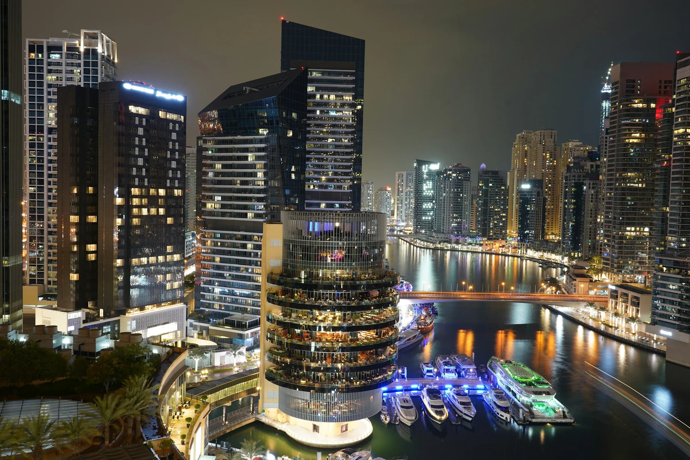 Waterfront towers and yachts along a marina canal at night