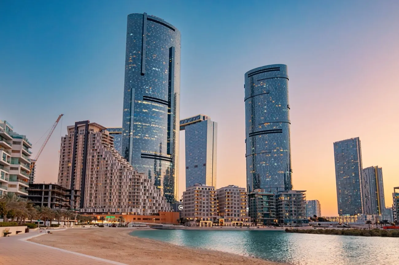 Residential towers and a beachfront promenade on Al Reem Island at sunset